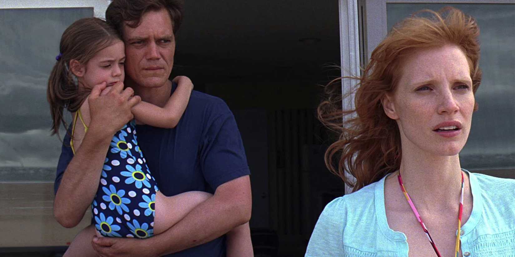 Curtis carries his daughter while his wife Samantha looks to the distance in Take Shelter