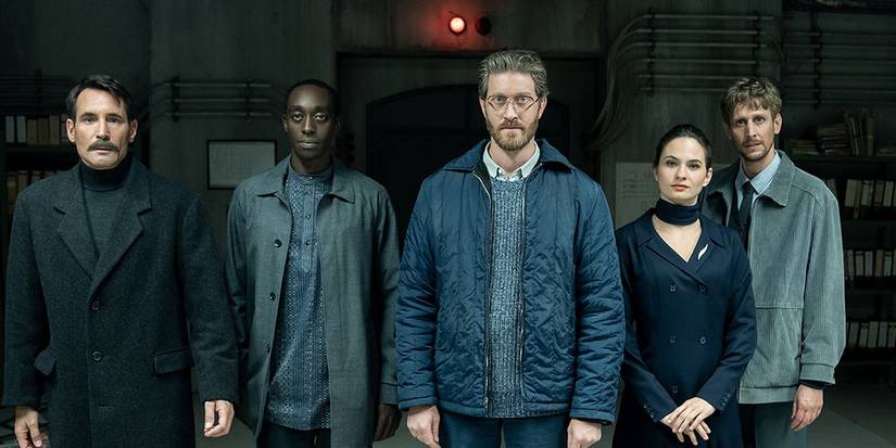 Team lineup from 'Counterpart' in front of a concrete passage with a red alarm light above it