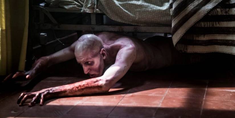 A creature crawls from under a bed in Terrified (2017).