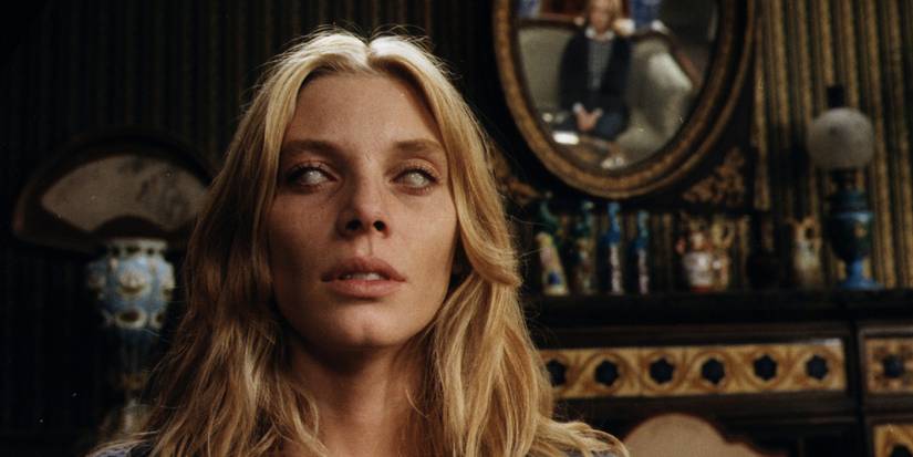 Liza Merril (Catriona MacColl) sits in a rooms with a photo behind her as her eyes go pure white in 'The Beyond' (1981).