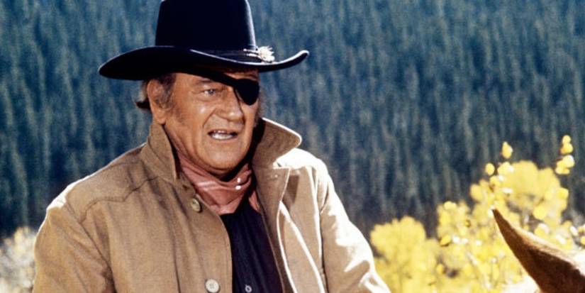 John Wayne as Rooster Cogburn with an eye patch on a horse in True Grit.