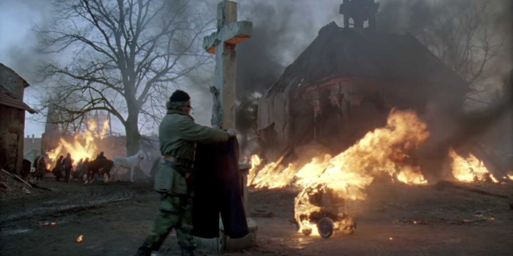A man standing with a cross while the background is in flames in Underground (1995)