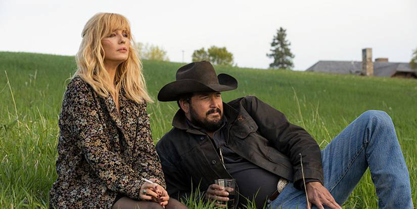 Kelly Reilly as Beth Dutton lounging in a grassy meadow with Cole Hauser as Rip in Yellowstone Season 5