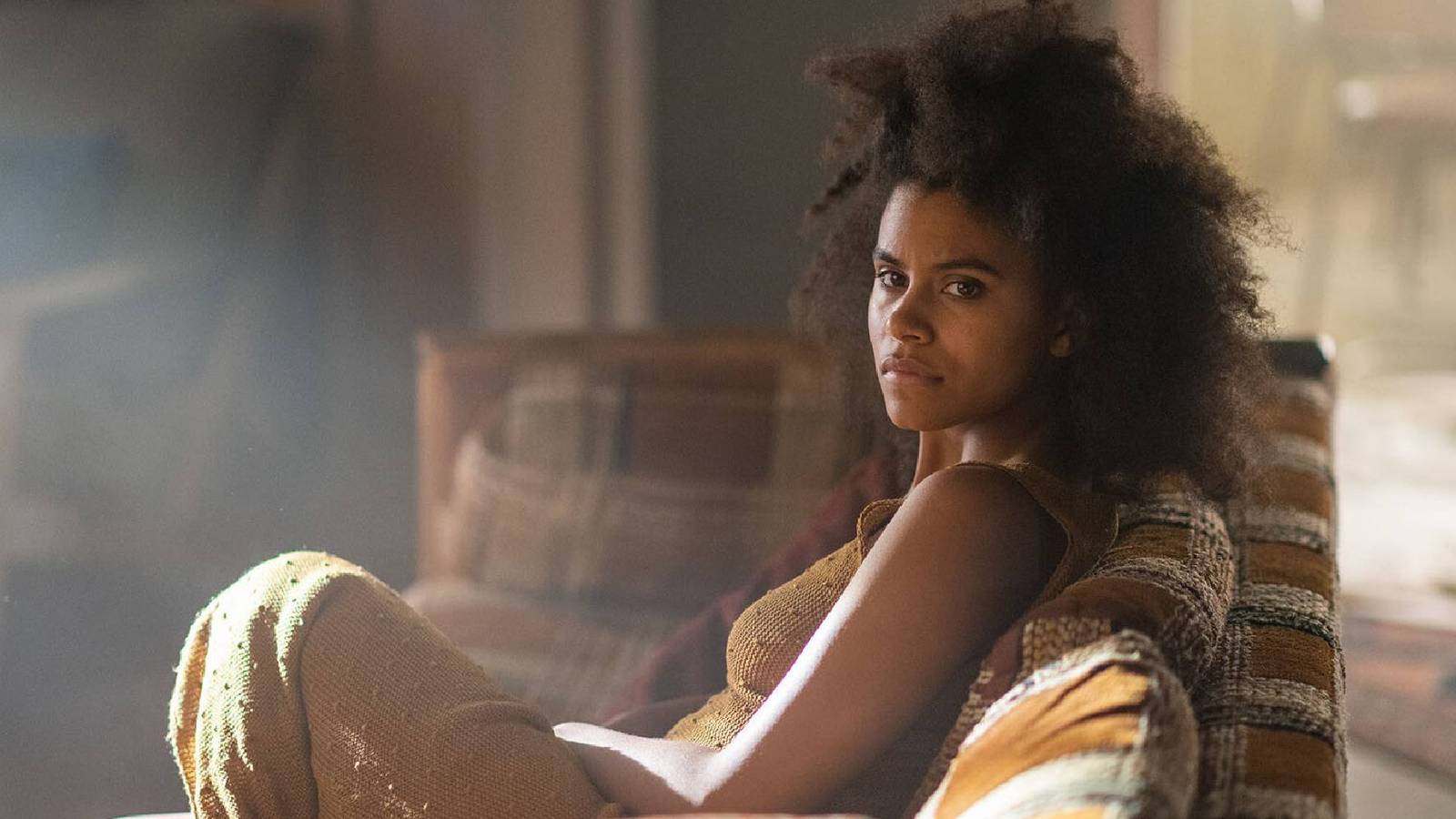 Zazie Beetz sitting on a couch while looking to her left in Nine Days.