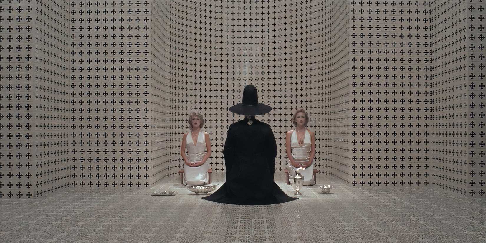 A witch and two women in a white room with black patterns in 'The Holy Mountain'