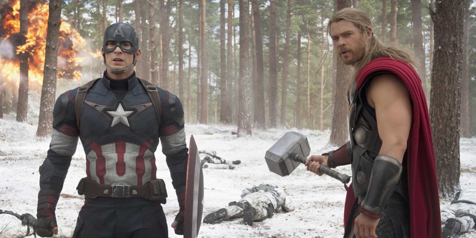 Captain America (Chris Evans) and Thor (Chris Hemsworth) stand next to each other on a snowy battlefield in 'Avengers: Age of Ultron' (2015).