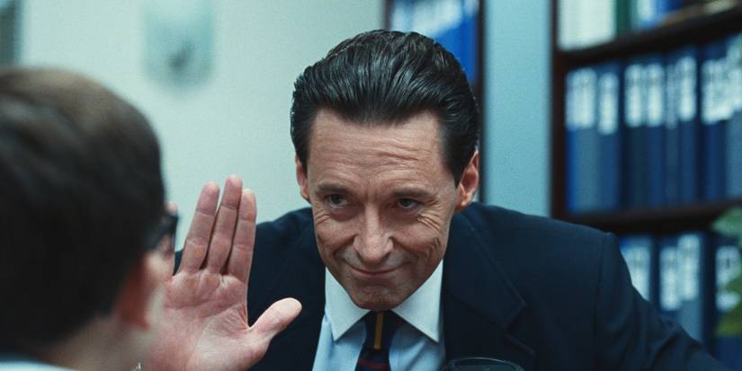 Hugh Jackman as Frank Tassone holding a hand up in Bad Education. 