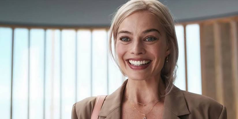 Margot Robbie as Barbie, standing in an office smiling in Barbie.