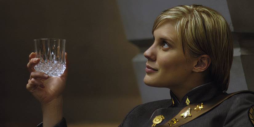 Kara Thrace looking offscreen to the left & smiling slightly while holding a drink in Battlestar Galactica