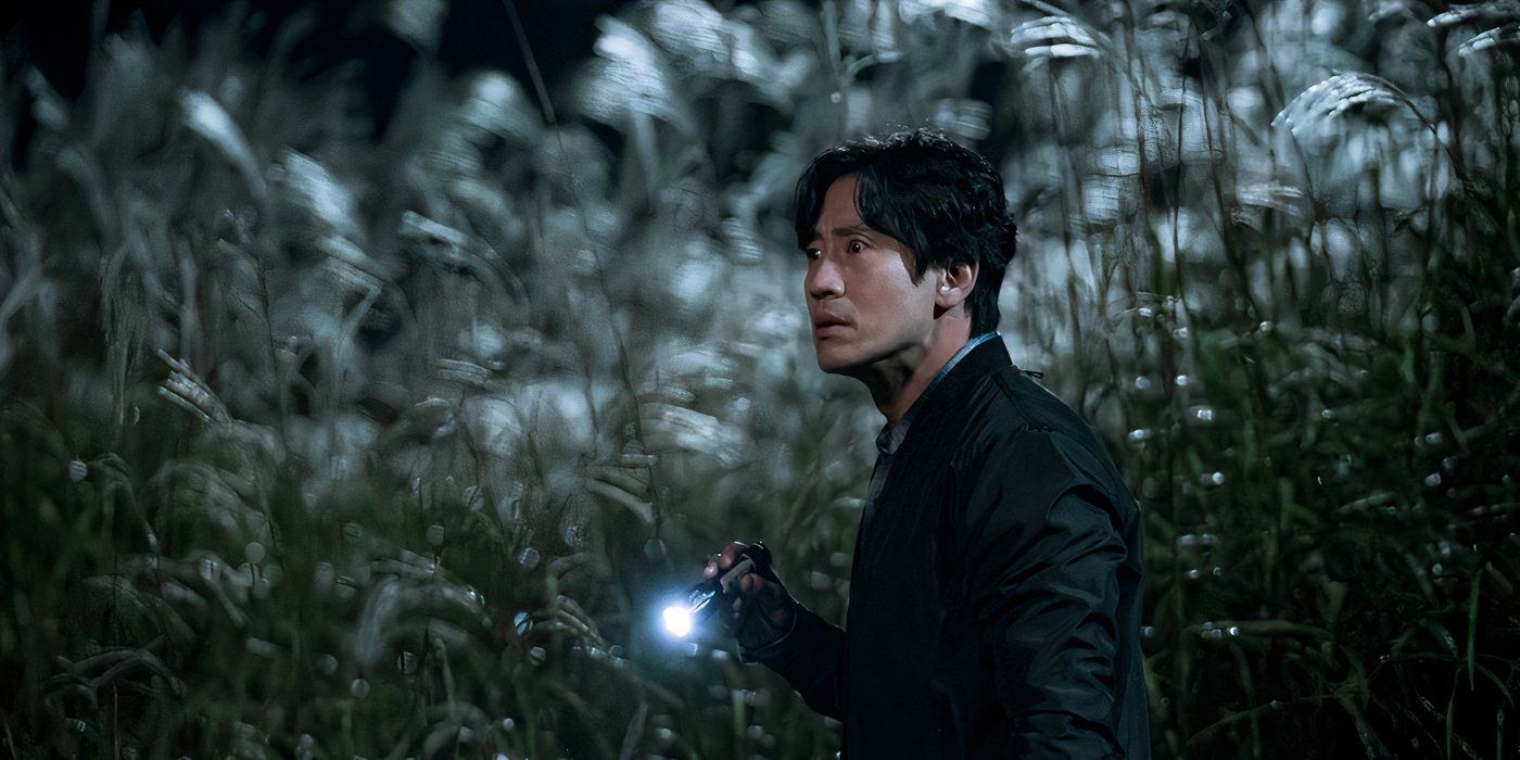 One of the cast stands in a field of tall plants at night, holding a flashlight in Beyond Evil.