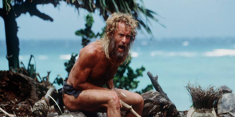 Tom Hanks as Chuck, with long shaggy hair and wearing a loincloth, screaming in Cast Away