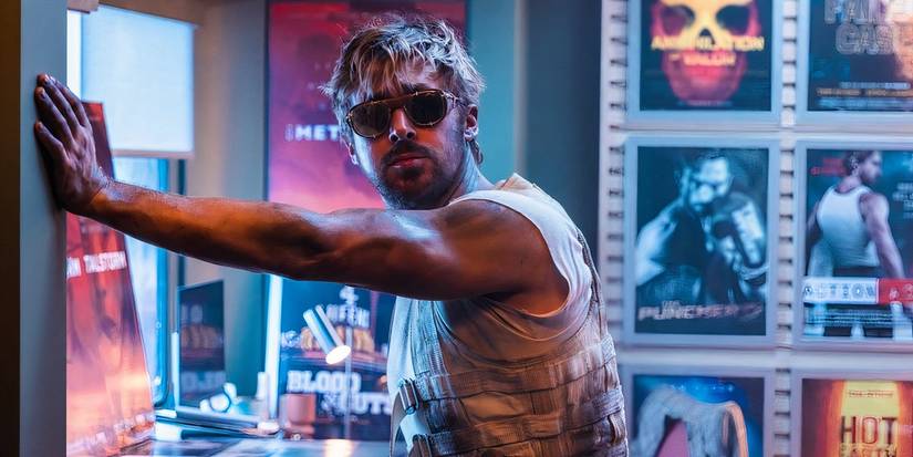 Ryan Gosling güneş gözlüğü ve kirli bir yelek giyen sonbaharda film afişleri dolu bir odada duruyor.