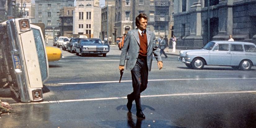 Clint Eastwood as Harry Callahan, holding a gun and walking through a street next to an overturned car in Dirty Harry