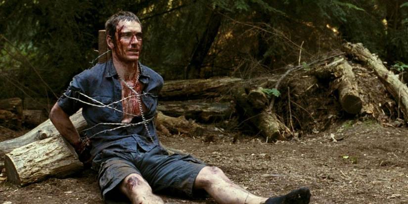 Michael Fassbender with a bloodied face tied to a pole in Eden Lake