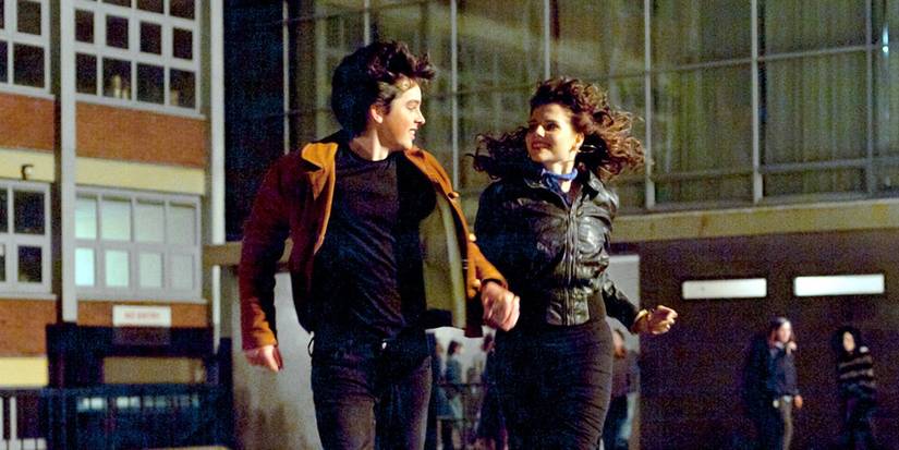 Ferdia Walsh Peelo and Lucy Boynton holding hands and running out of school in a scene from 'Sing Street'