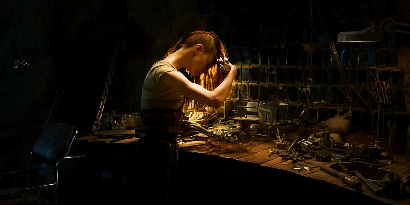 Anya Taylor-Joy shaves her head in a dim workshop in 'Furiosa