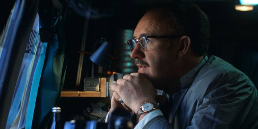 Gene Hackman in glasses looking at a screen, his chin resting on his hands in The Conversation.