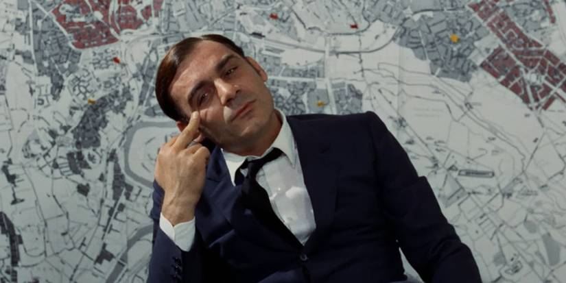 Gian Maria Volontè in front of a map, touching his eye, in 'Investigation of a Citizen Above Suspicion'