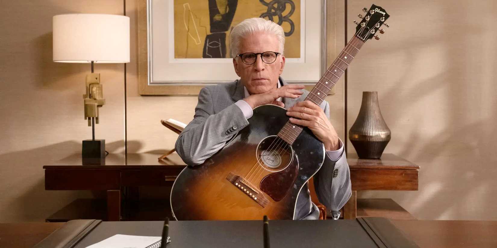 Michael with a guitar sitting at a desk in the series finale ofThe Good Place, Whenever You're Ready.