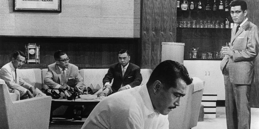Toshirō Mifune as Kingo Gondo sitting solemnly while his cast mates watch in High and Low