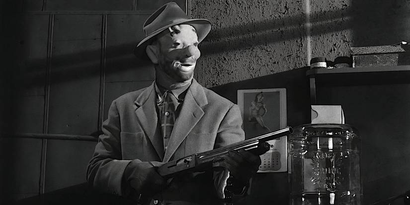 A person in a clown mask wears a hat and holds a shotgun in The Killing.