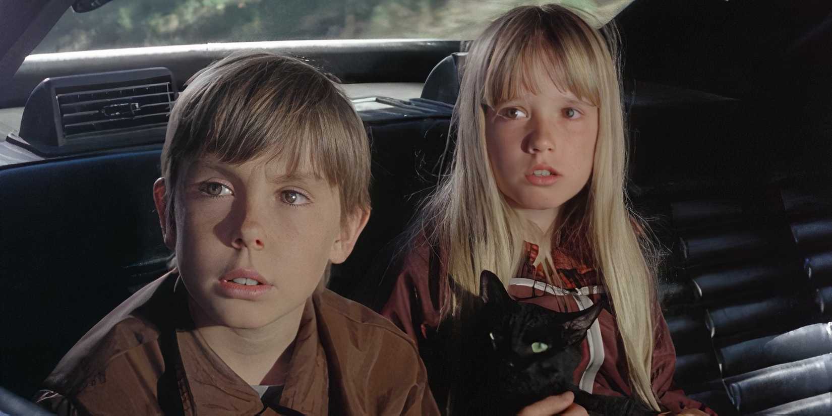 Kim Richards and Ike Eisenmann look out a car window anxiously in Escape to Witch Mountain, 1975
