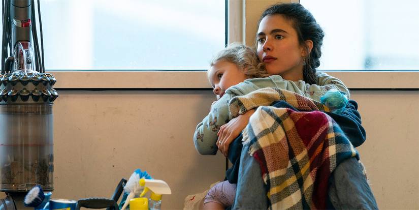 Margaret Qualley as Alex hugging her daughter while sitting on the ground in the show Maid