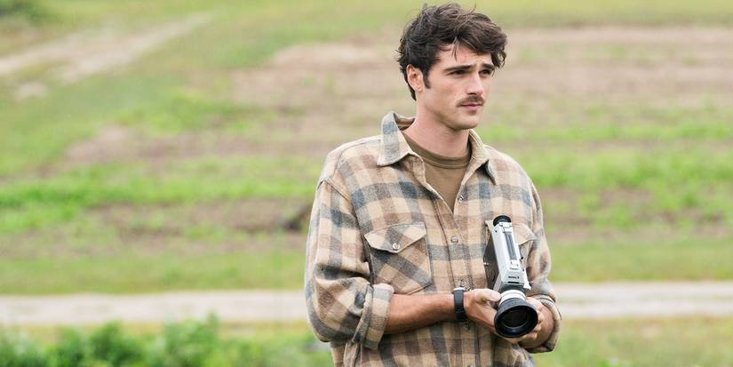 Jacob Elordi as Leonard Fife with a mustache in plaid on a field holding a camera in Oh, Canada.
