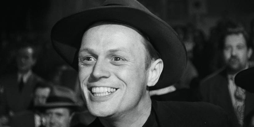 Richard Widmark as Tommy Udo smiling widely in the midst of a crowd of people in Kiss of Death (1947)