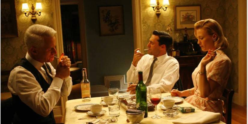 John Flaherty, John Hamm, and January Jones as Roger, Don, and Betty smoking cigarettes at the dinner table in 'Mad Men'