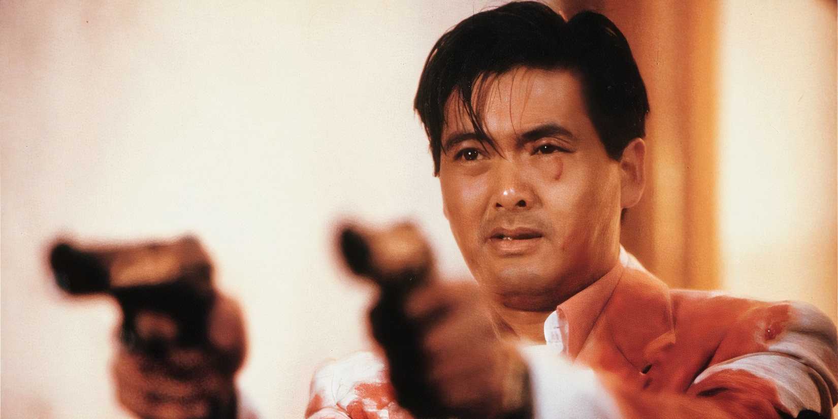 A bloodied Chow Yun-fat holding two guns in The Killer (1989).