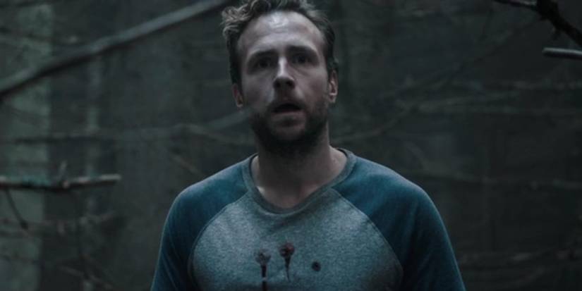 Rafe Spall as Luke looking frightened in the woods in 2017's The Ritual
