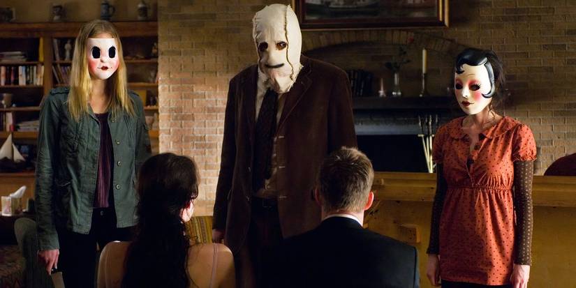 The three killers look at their two victims, who are tied to chairs in The Strangers.