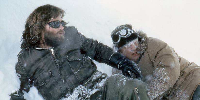 Kurt Russell and Charles Hallahan as MacReady and Norris, lying in the snow looking shocked in The Thing