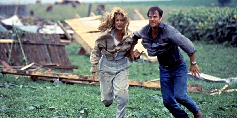 Helen Hunt and Bill Paxton as Dr. Jo and Bill Harding, running through a field full of debris in Twister