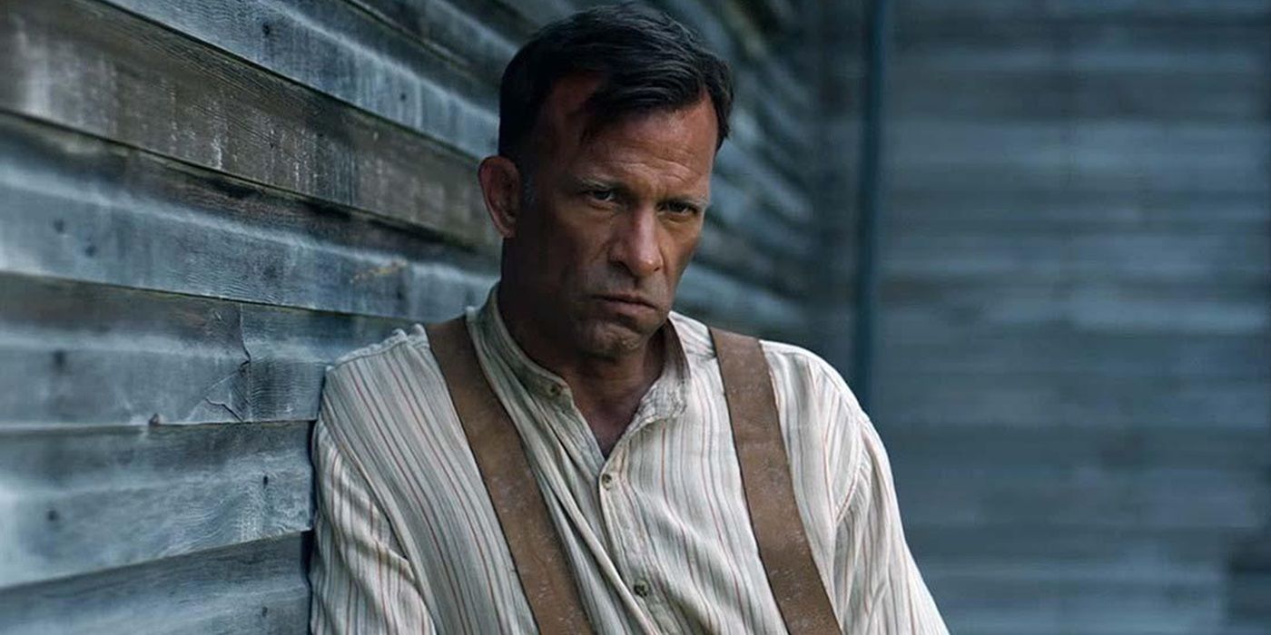 Thomas Jane as Wilfred James leaning on a wall and looking suspiciously at a person offscreen in 1922