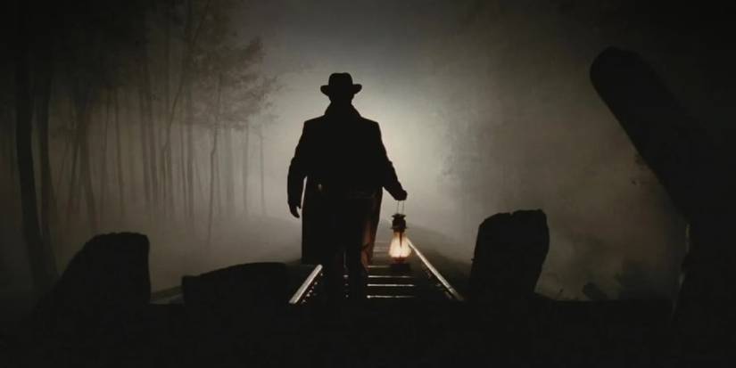 A man holding a lamp while walking in the middle of train tracks in The Assassination of Jesse James.
