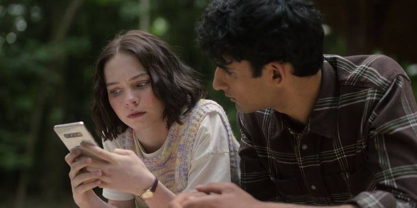Emma Myers and Zain Iqbal look at a phone in ‘A Good Girl’s Guide to Murder.’