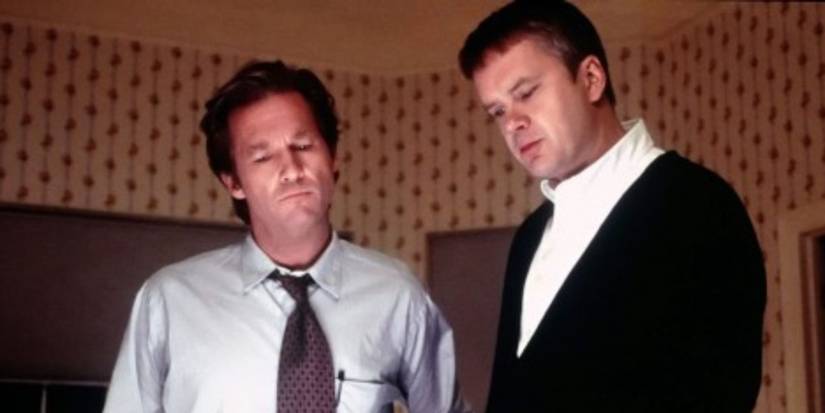 Michael Faraday (Jeff Bridges) wears a shirt and tie as he stands alongside Oliver Lang (Tim Robbins) in his house in 'Arlington Road' (1999).