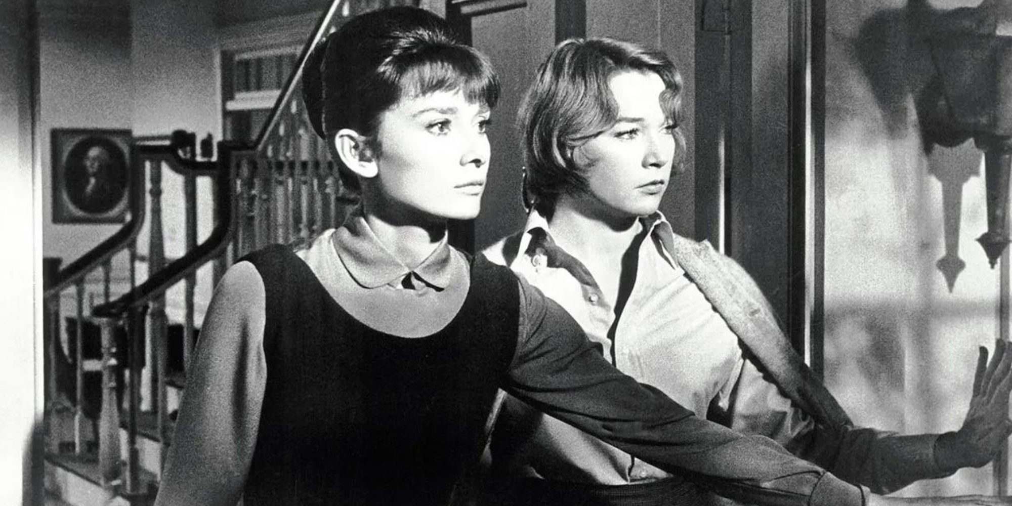 Audrey Hepburn standing with Shirley MacLaine in an open doorway looking out in The Children's Hour (1961)