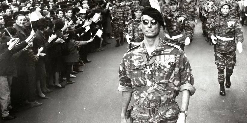 A military officer in sunglasses and a beret leads soldiers through a crowd in The Battle of Algiers, 1966.