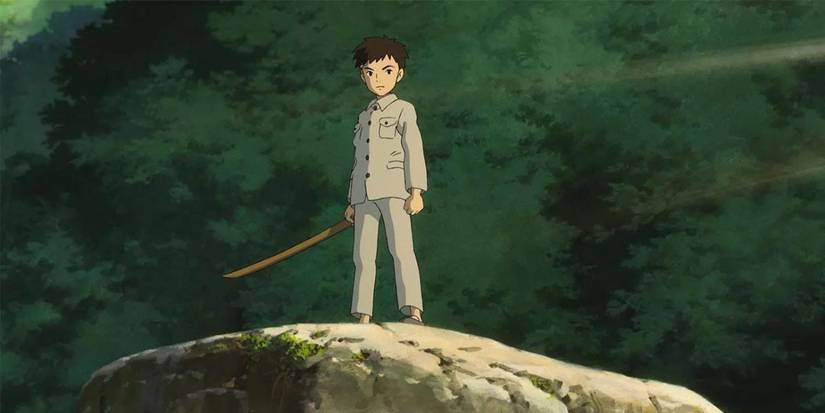 Mahito holding a fake blade while standing on stop of a rock in The Boy and the Heron.