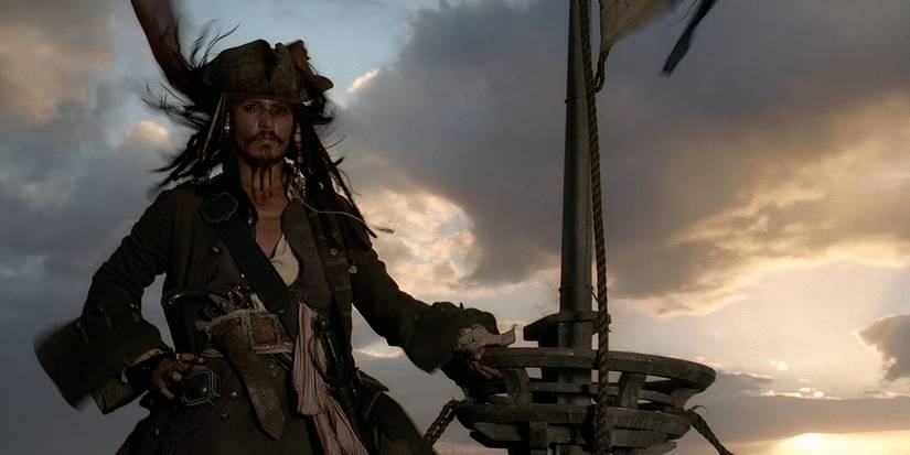 Captain Jack Sparrow stands in the crow's nest of a ship, looking triumphantly out over the horizon