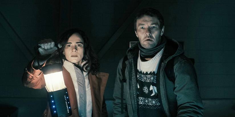 Alice Braga holds up a lantern next to Joel Edgerton dressed in puffy jackets looking shocked
