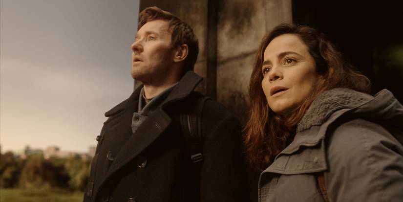 Joel Edgerton and Alice Braga wearing coats looking around them in wonder
