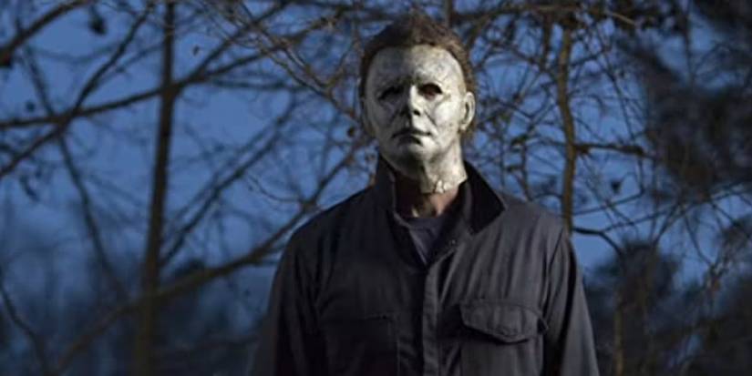 Michael Myers standing outside and looking at a person offscreen in Halloween 2018.