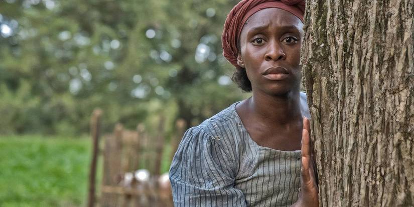 Cynthia Erivo as Harriet Tubman as she watches something from behind a tree