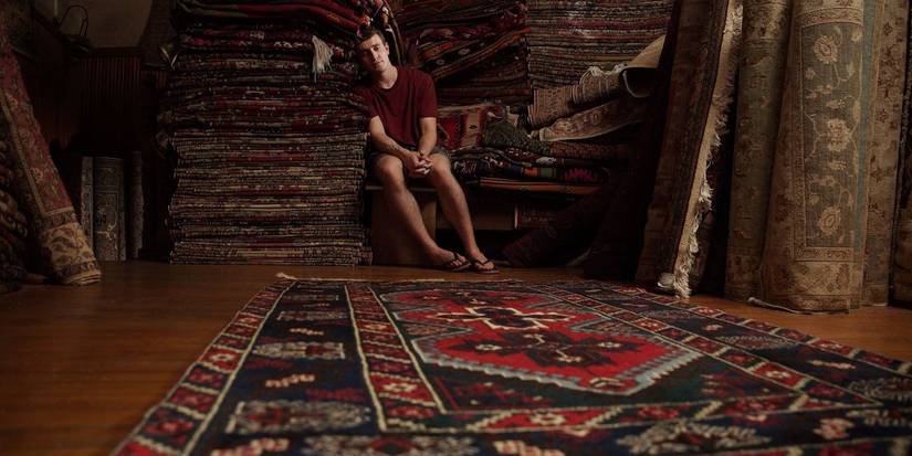 Paul Mescal as Calum sitting alone in a rug store in a still from Aftersun. 