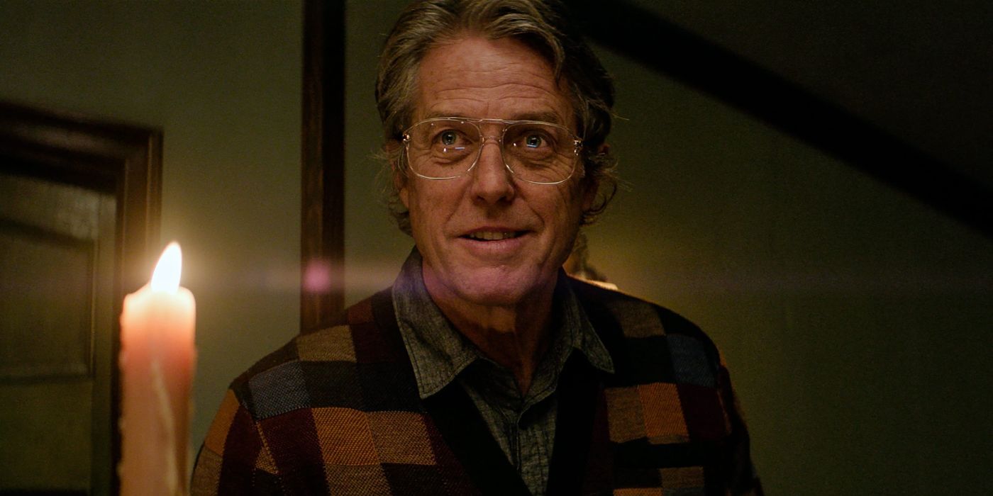 Hugh Grant as Mr. Reed in Heretic, standing in candlelight.