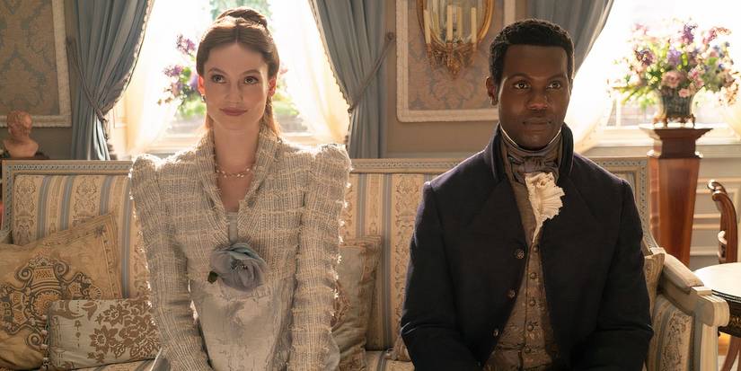 Francesca Bridgerton and John Stirling sit next to each other on a sofa in 'Bridgerton'